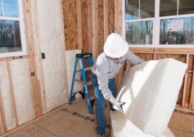 Austin Company | installing white fiberglass insulation in home