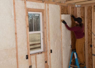 Austin Company | worker installing white fiberglass insulation