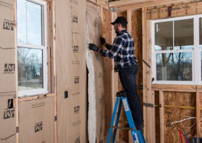 Austin Company | installing fiberglass insulation in walls of home