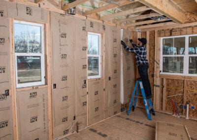 Austin Company | worker installing white fiberglass insulation